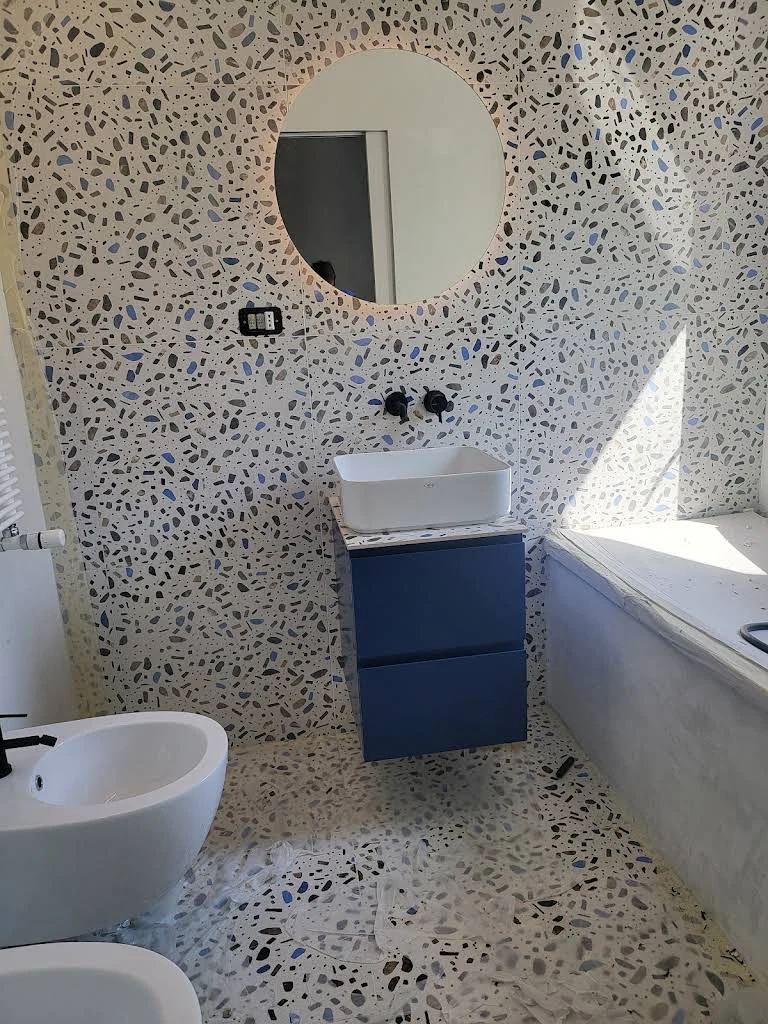 Bagno con rivestimento a mosaico e specchio tondo